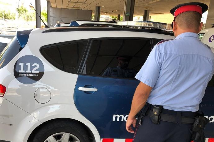 Agente y coche de Mossos d'Esquadra.