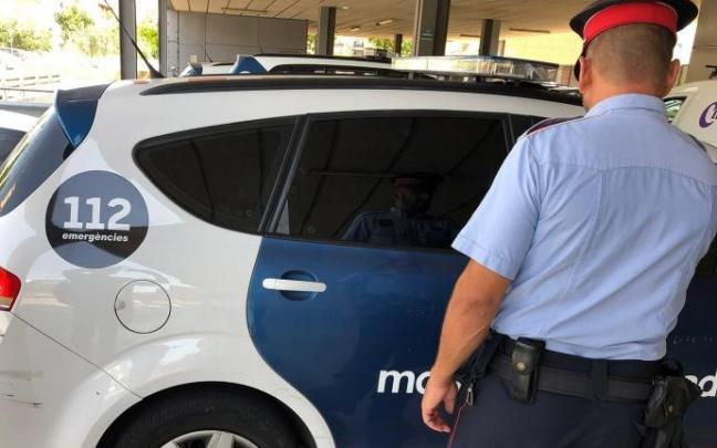 Agente y coche de Mossos d'Esquadra.