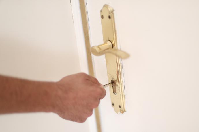 Un hombre introduce una llave en la cerradura de la puerta de una vivienda.