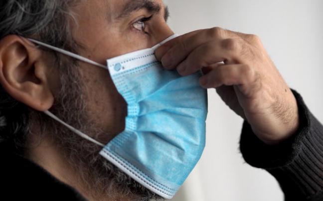 Un hombre se coloca una mascarilla.