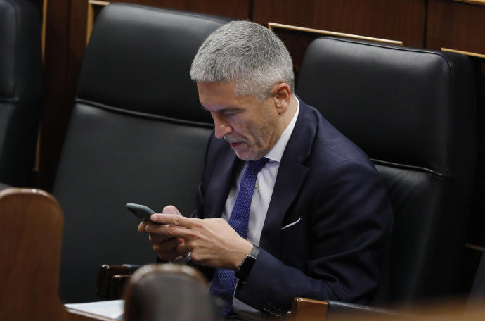 El ministro del Interior, Fernando Grande Marlaska, consulta su móvil.
