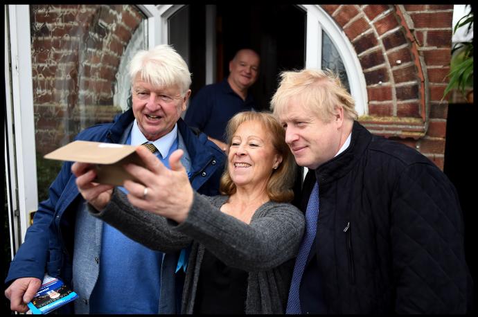 Boris Johnson junto a su padre, Stanley, se hacen una foto con una votante conservadora.