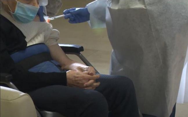 Una sanitaria vacuna a un anciano Una sanitaria vacuna a un anciano