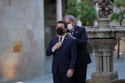 El expresidente Quim Torra pone la medalla de presidente de la Generalitat a Pere Aragonès.