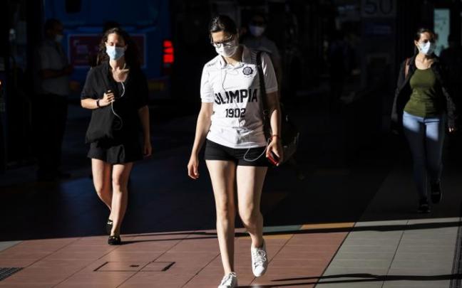 Imagen de archivo de personas paseando por la calle con mascarilla.