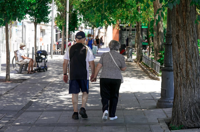 Una pareja de ancianos camina por la calle cogida de la mano.