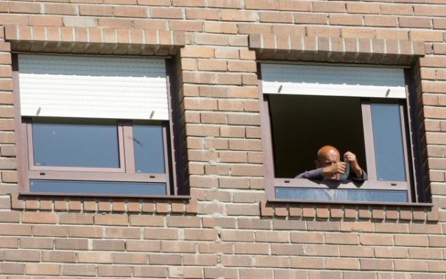 Un hombre se coloca su mascarilla en la habitación de una residencia Un hombre se coloca su mascarilla en la habitación de una residencia