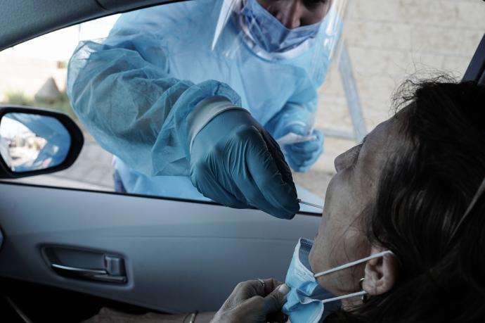 Un trabajador de la salud toma un hisopo de una mujer para una prueba de PCR de coronavirus.