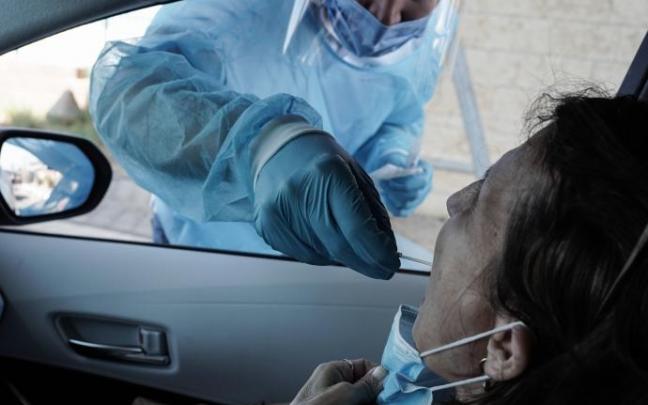 Un trabajador de la salud toma un hisopo de una mujer para una prueba de PCR de coronavirus. Un trabajador de la salud toma un hisopo de una mujer para una prueba de PCR de coronavirus.