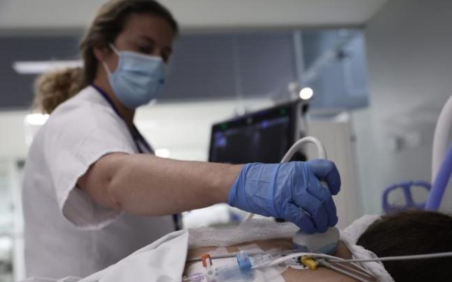 Una sanitaria realiza una ecografía a una paciente en la UCI.