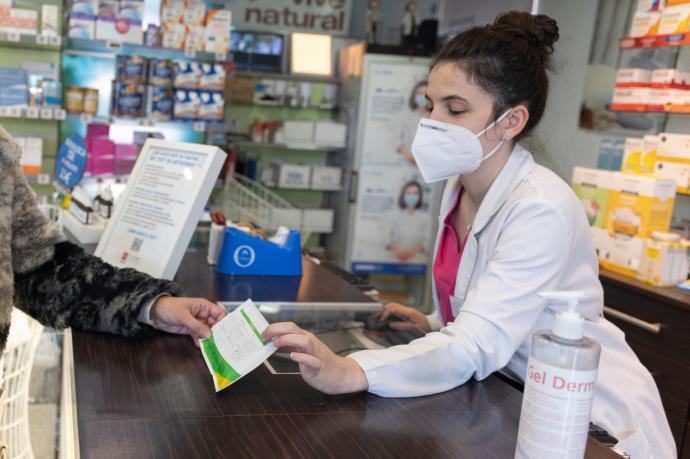 Una farmacéutica muestra un test de antígenos a una persona en la farmacia 'Las Gemelas', Madrid.