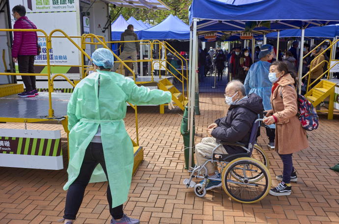 Un hombre en silla de ruedas acude a un centro de salud a realizarse la prueba de detección del covid, Hong Kong.