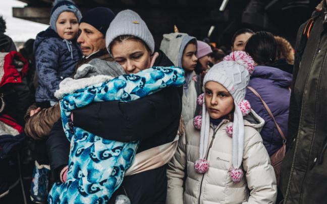 Varias personas con niños esperan para cruzar el río de Irpin.