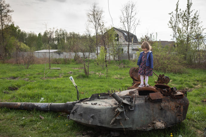 Una niña se para en la torre de un tanque ruso destruido cerca de Makariv.