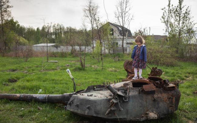 Una niña se para en la torre de un tanque ruso destruido cerca de Makariv.