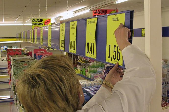 Una dependienta coloca los precios de los productos en su comercio.