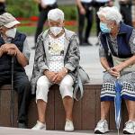 Tres personas mayores, protegidas con mascarilla, charlan en un banco, ayer en Donostia. Foto: Juan Herrero / Efe