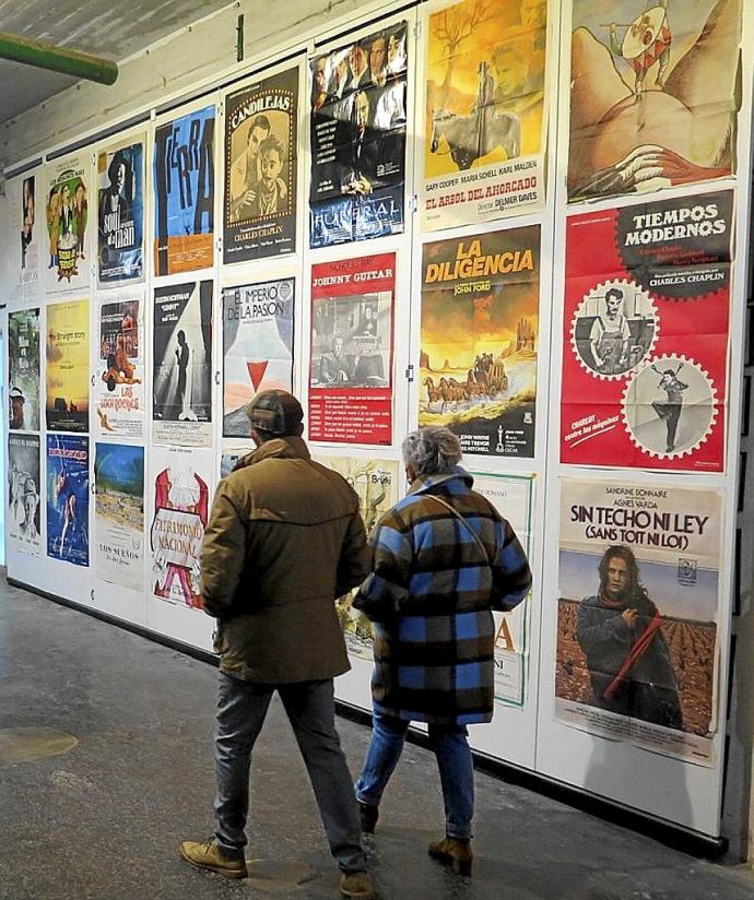 Una pareja pasa delante de una pared repleta de carteles de películas.