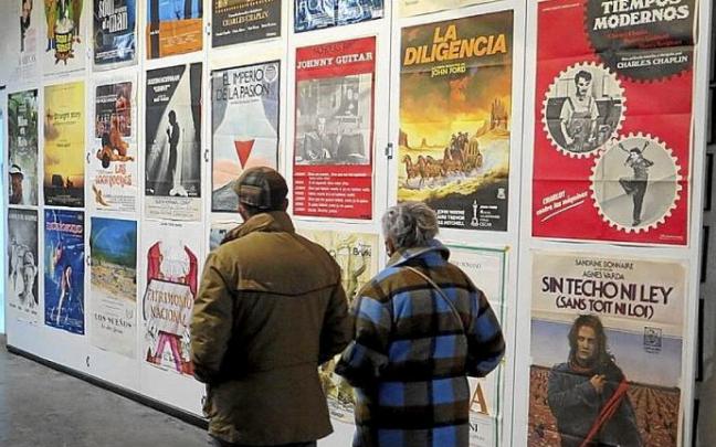 Una pareja pasa delante de una pared repleta de carteles de películas.
