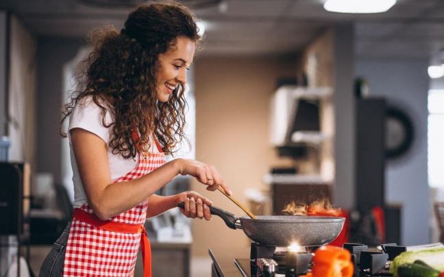 Una mujer cocina verduras en una sartén. Una mujer cocina verduras en una sartén.