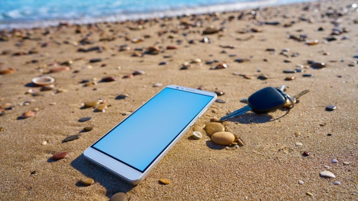 Un teléfono móvil y unas llaves, dos objetos que pueden ser robados, en una playa.