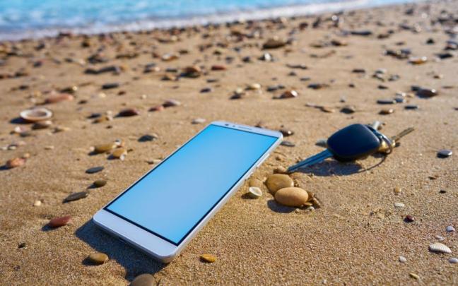 Un teléfono móvil y unas llaves, dos objetos que pueden ser robados, en una playa.