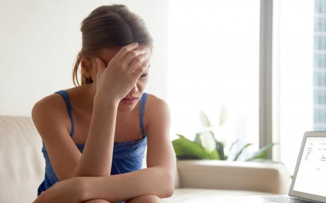 Una mujer sentada con dolor de cabeza.