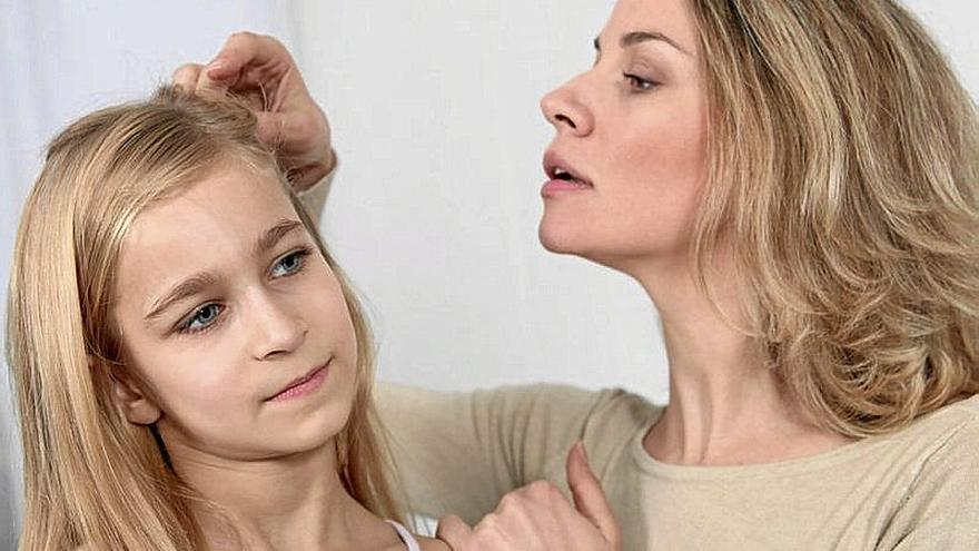 Una madre comprueba si su hija tiene piojos en el cabello.