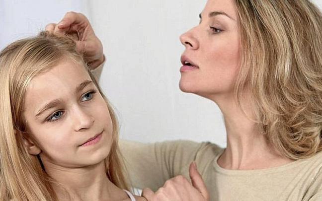 Una madre comprueba si su hija tiene piojos en el cabello.