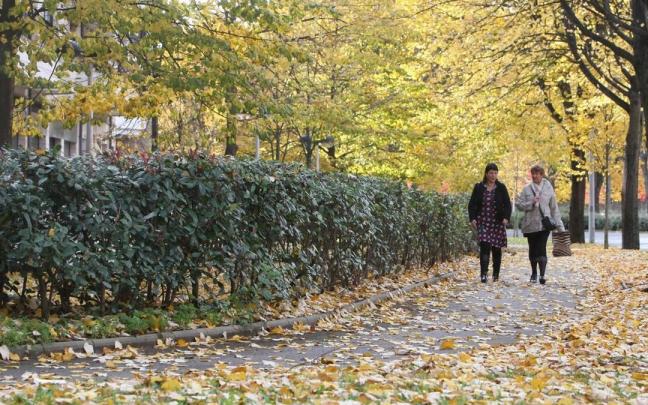 Dos mujeres pasean por un bidegorri cubierto de hojas por el otoño en Donostia