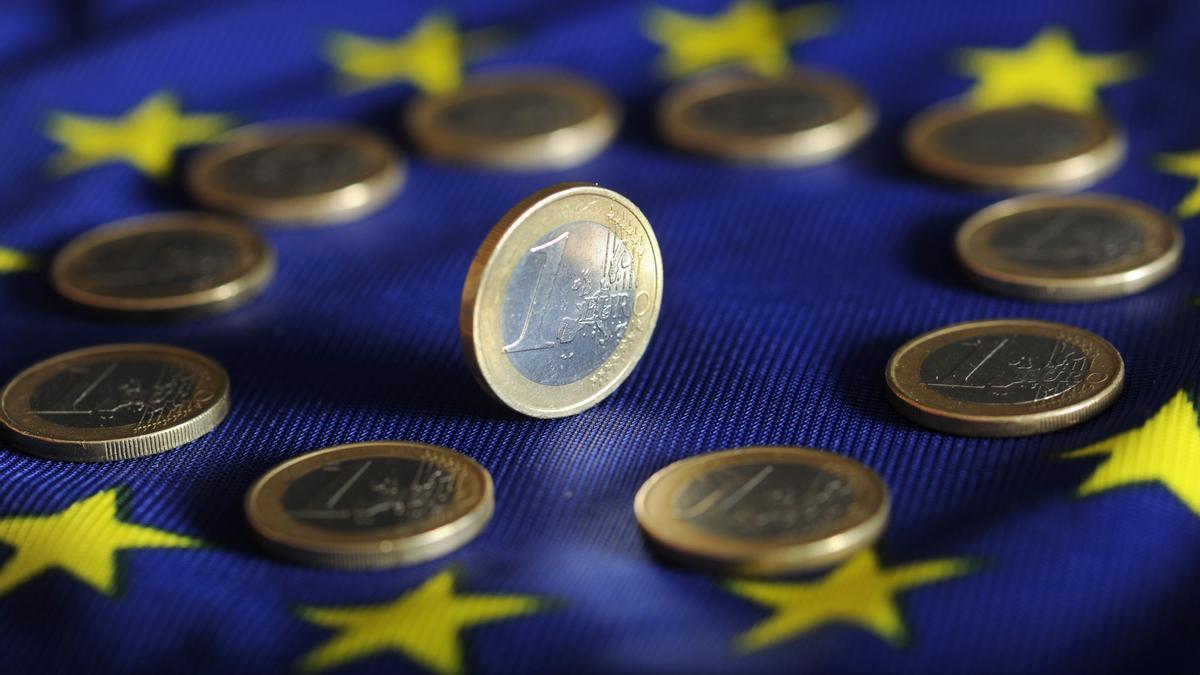Monedas de euro sobre el logo de la Unión Europea.