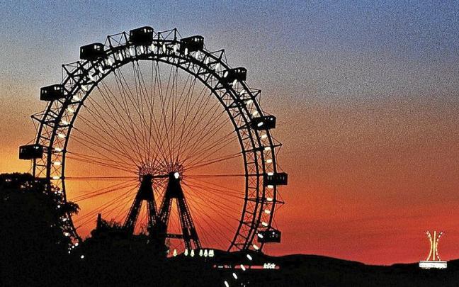 La silueta de la noria se dibuja sobre el cielo al anochecer.