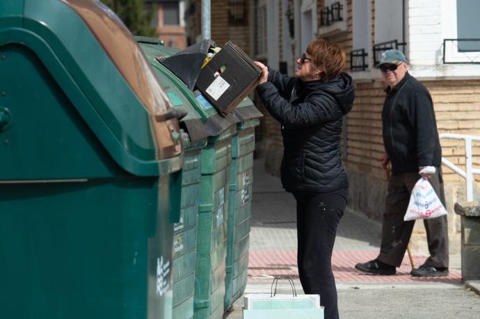 Una mujer tira basura al contenedor.