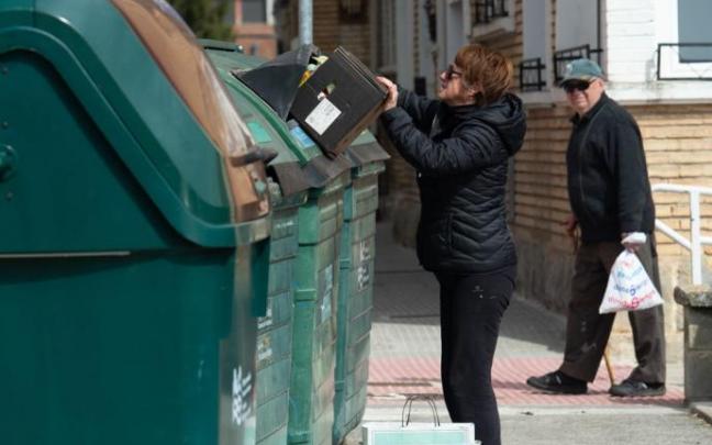 Una mujer tira basura al contenedor.