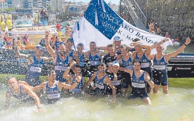 Los remeros de Urdaibai celebran, con la bandera en sus manos, el triunfo en la rampa del muelle donostiarra.
