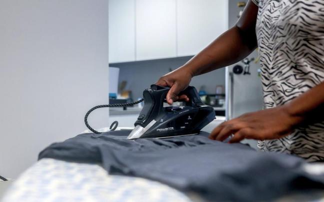 Una empleada de hogar plancha una camiseta.
