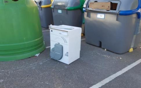 Una lavadora abandonada junto a los contenedores.