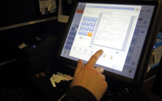 Un comerciante cobra uno de sus servicios en una caja registradora. Un comerciante cobra uno de sus servicios en una caja registradora.
