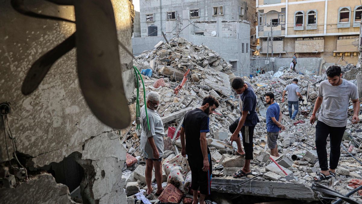 Varios palestinos caminan entre los escombros de un edificio destruido