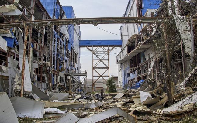 Un hombre pasea entre los restos de una f&aacute;brica destruida en J&aacute;rkov.