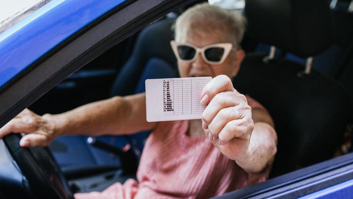 Una mujer mayor muestra por la ventanilla su carné de conducir.