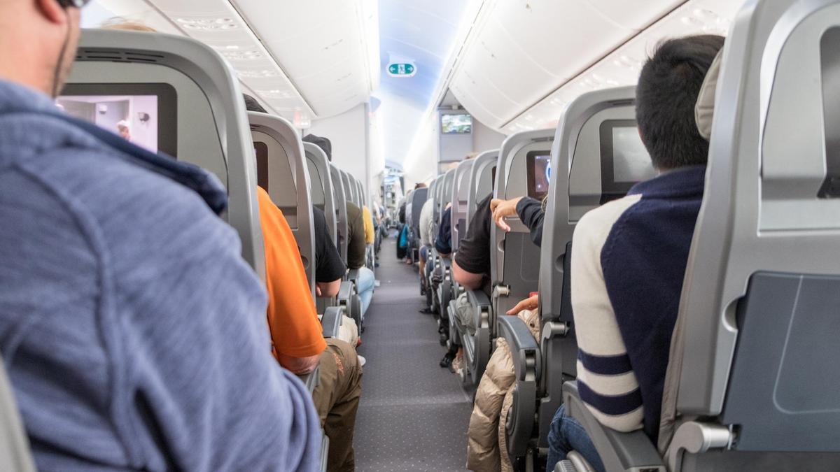 Pasajeros ocupan sus asientos en la cabina de un avión.