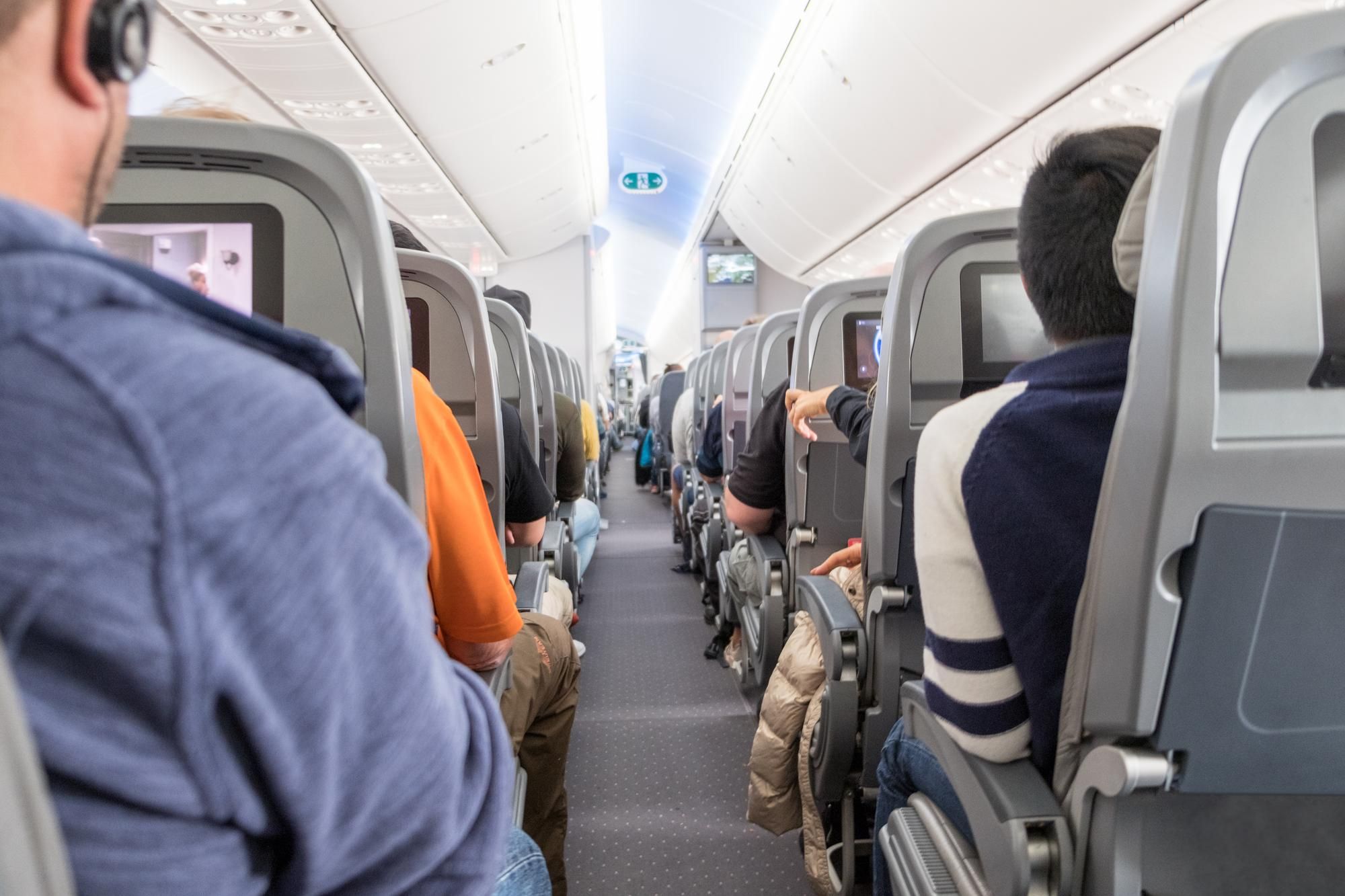 Pasajeros ocupan sus asientos en la cabina de un avión.