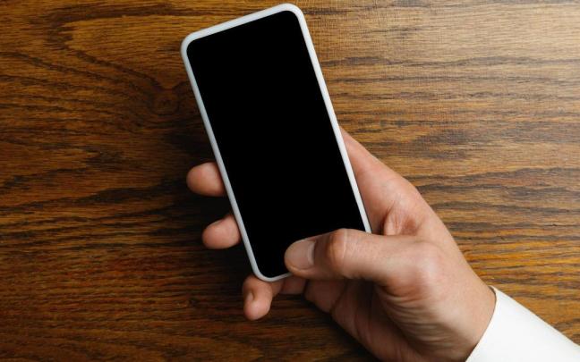 Un hombre maneja el m&oacute;vil con el dedo pulgar.