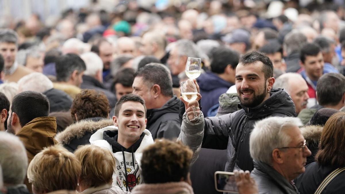 Dos personas disfrutando del txakoli en medio del gentío, en el frontón de Getaria, este martes, día de San Antón.