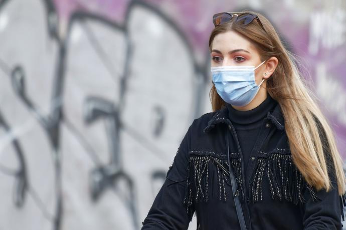 Una mujer camina protegida por una mascarilla.