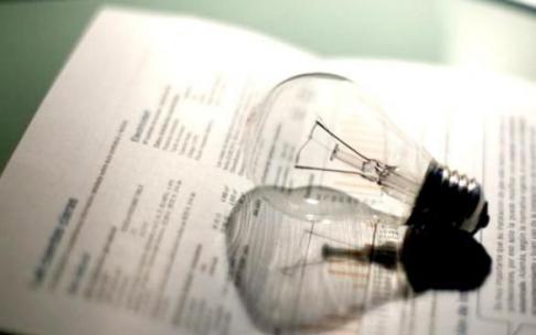 Una bombilla junto a la factura de la luz.