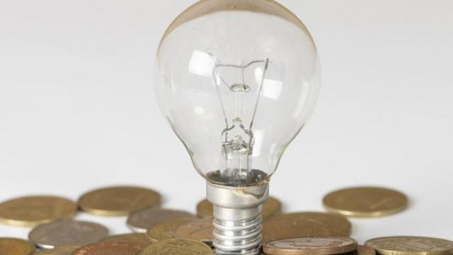 Imagen de una bombilla sobre monedas de euro.