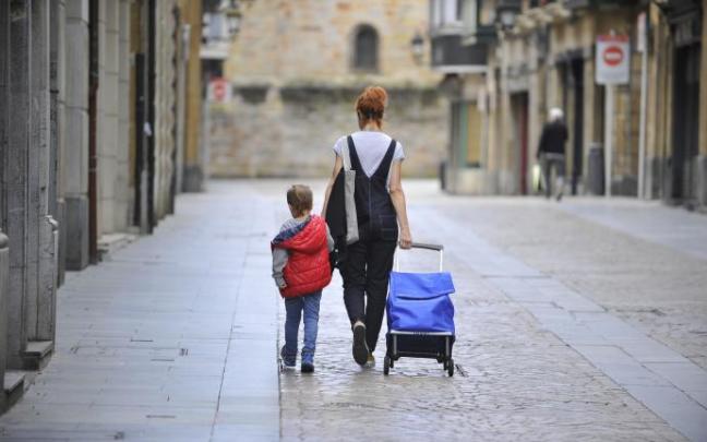 Una mujer, tirando del carro de la compra, y un niño caminan por las calles del Casco Viejo de Bilbao. Una mujer, tirando del carro de la compra, y un niño caminan por las calles del Casco Viejo de Bilbao.