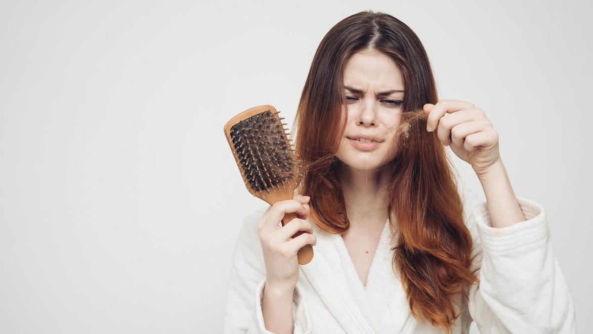 Una mujer retira del cepillo pelos de su melena.